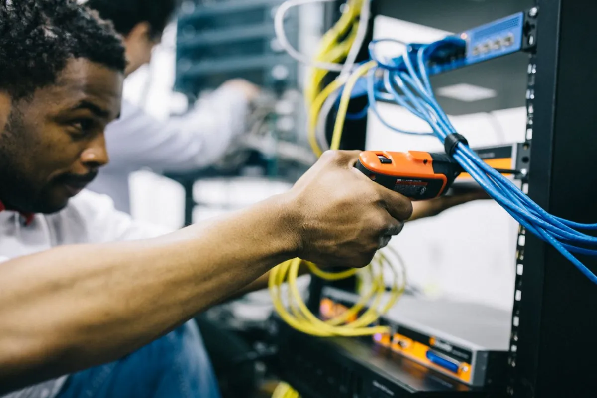 Técnico trabalhando na fiação de um rack de rede industrial